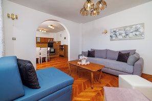A living room with a sofa, a coffee table, and a dining area with chairs and a table. - Apartment Antonija (Novi Vinodolski)
