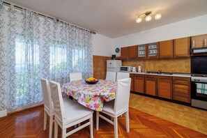 A kitchen with wooden cabinets, a microwave, and a stove. - Apartment Antonija (Novi Vinodolski)