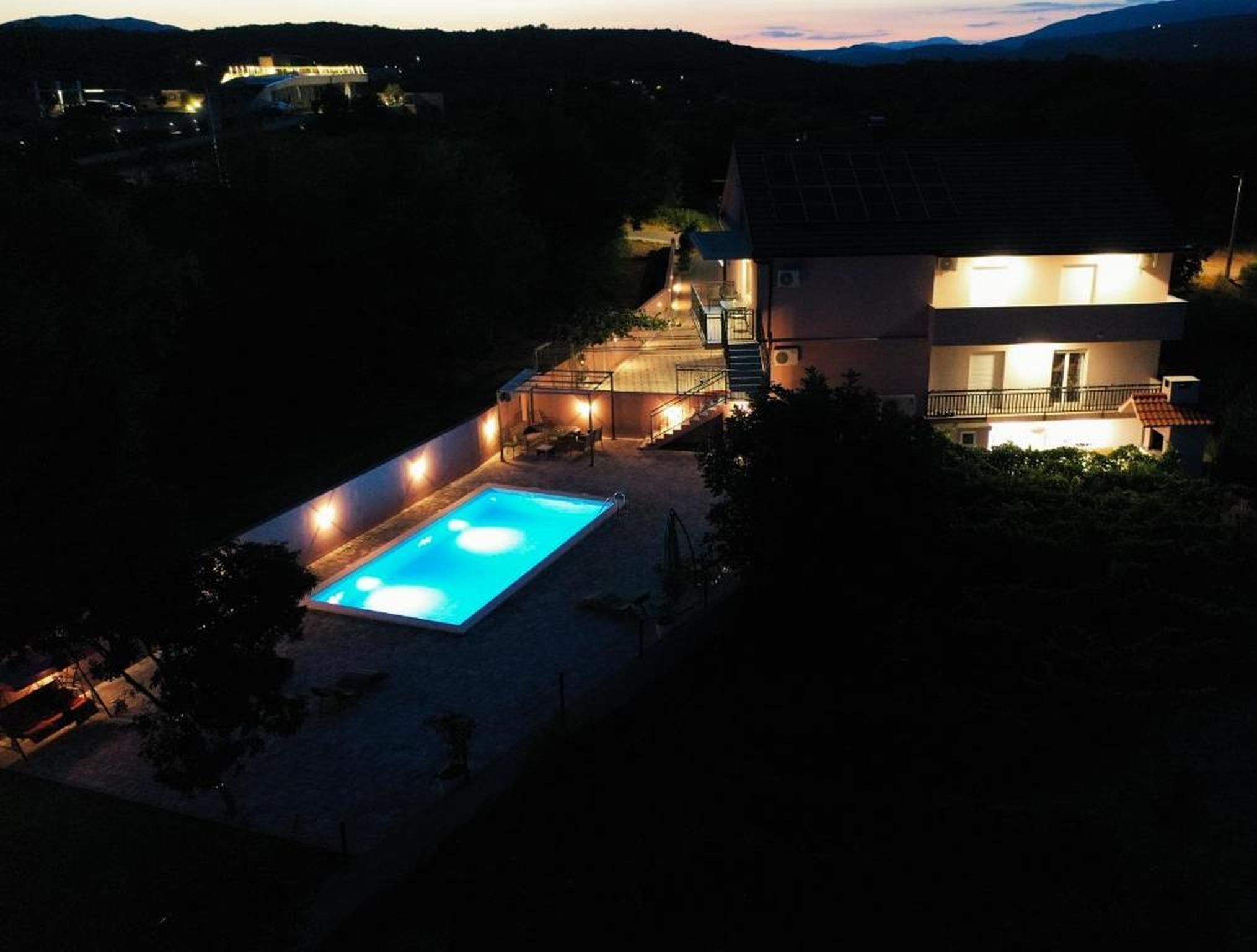 A two-story building with a swimming pool, outdoor lighting, and a staircase leading to the upper floor.