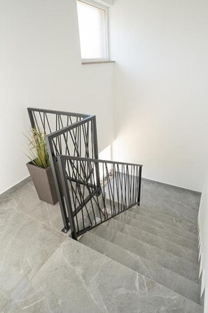 A staircase with a metal railing, a potted plant, and a window. - Apartment Hope (Zmijavci)