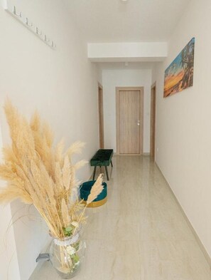 A hallway with a vase of dried plants, a green bench, and a wooden door at the end. - Apartment Hope (Zmijavci)