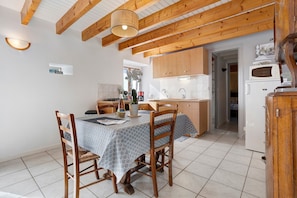 Une cuisine de taille réduite avec des meubles de rangement en bois, une table à manger avec des chaises et un sol carrelé.