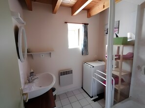 A small bathroom with a sink, mirror, radiator, and a window with a curtain.