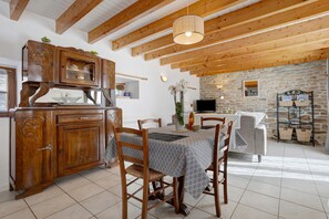 Un espace repas avec une table en bois, des chaises et un mur en pierre.