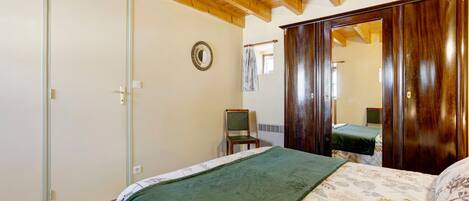Quarto com cama, cadeira, guarda-roupa e espelho.