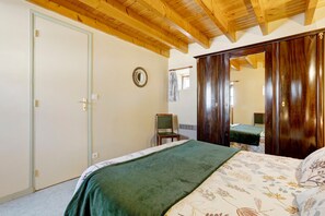 A bedroom with a bed, a chair, a wardrobe, and a mirror.