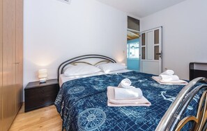 A bedroom with a bed, a nightstand, a lamp, and a door leading to another room. - House Veronika (Primosten)