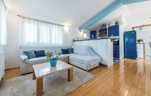 A modern living room with a sofa, a coffee table, and a kitchen area with cabinets and appliances. - House Veronika (Primosten)