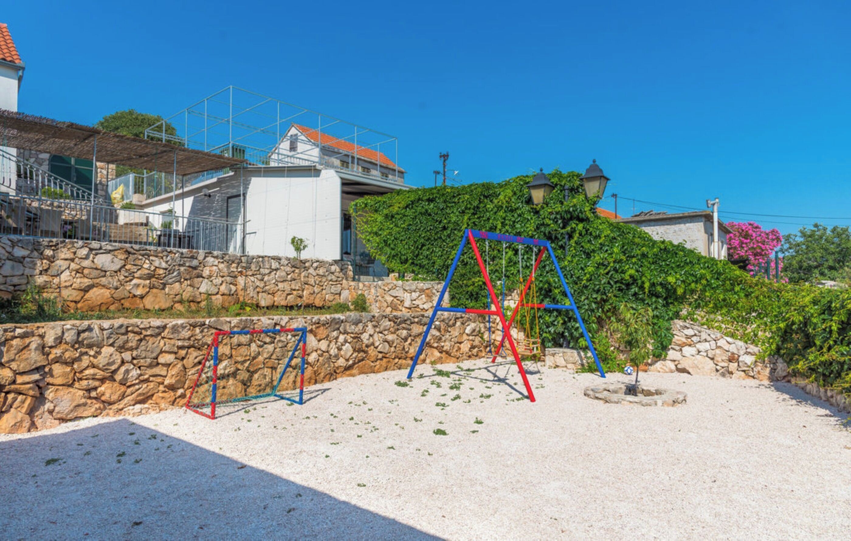 Ein Spielplatz mit Schaukeln und einer Steinmauer.
