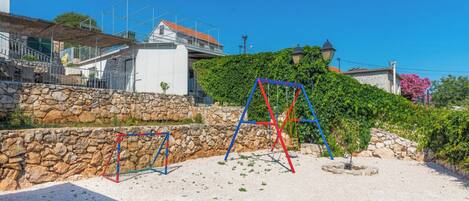 Un terrain de jeux avec des balançoires et un mur en pierre.