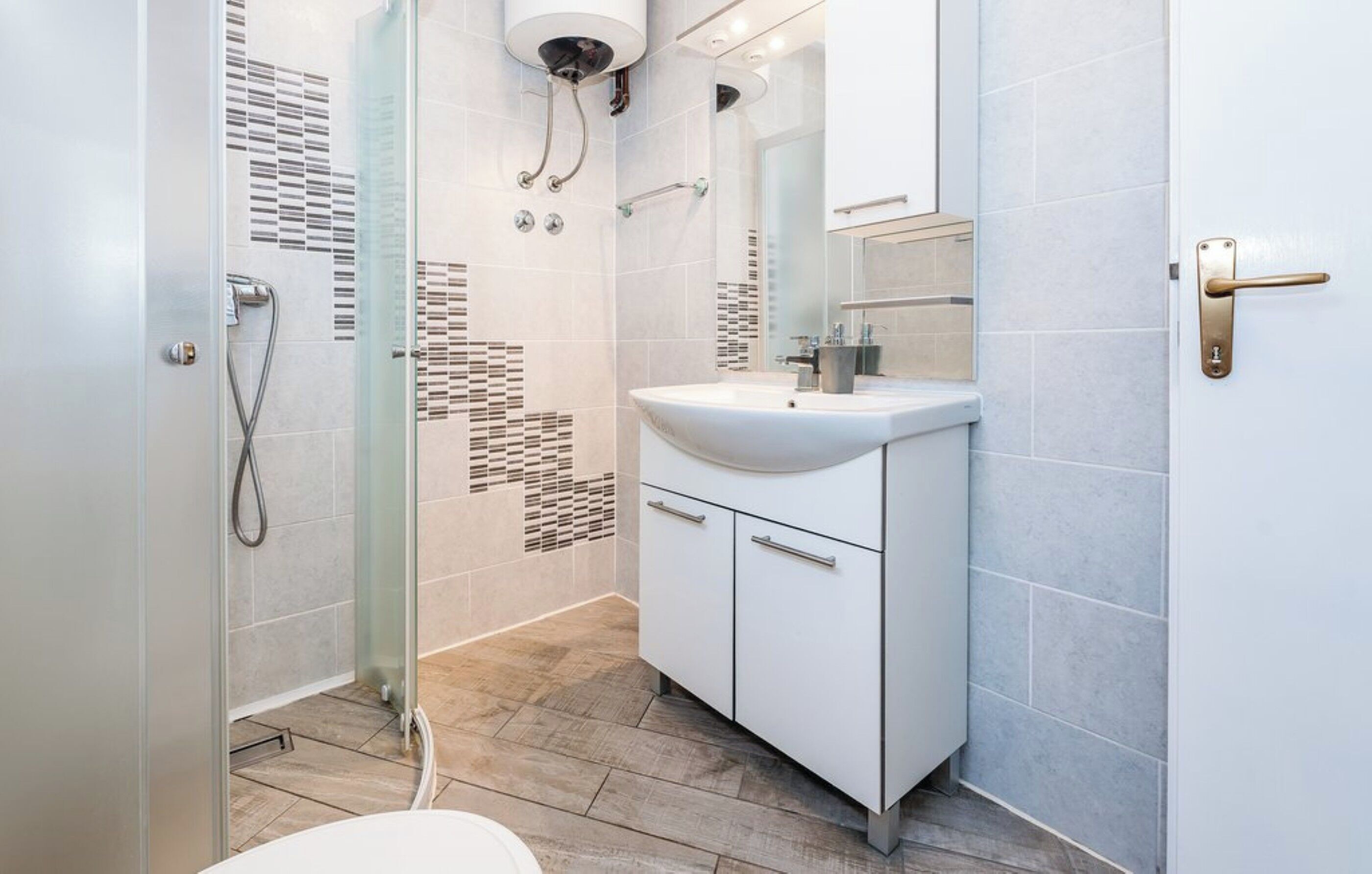 Ein modernes Badezimmer mit Duschkabine aus Glas, einem weißen Waschbecken und Fliesenboden.