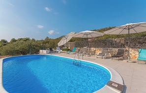 A swimming pool with lounge chairs and umbrellas, surrounded by a stone wall and greenery. - House Veronika (Primosten)