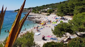 Ein Strand mit Menschen, Sonnenschirmen und einer felsigen Küstenlinie.