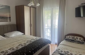 Ein Schlafzimmer mit einem Bett, einem Kleiderschrank, einem Fernseher und einem Fenster mit Vorhängen.