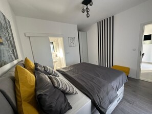 Een moderne slaapkamer met een groot bed, een nachtkastje, een spiegel en een deur naar de badkamer.
