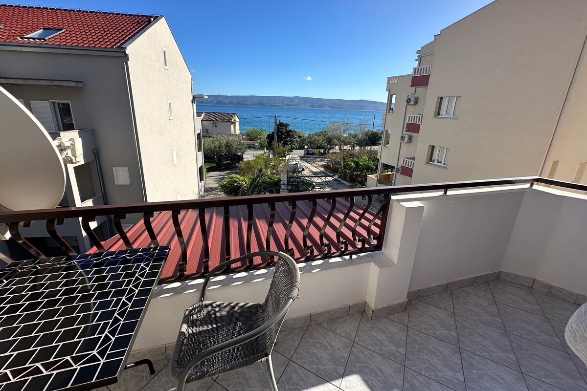 A balcony with a view of the sea, a satellite dish, and a chair.