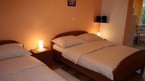A bedroom with two beds, a nightstand with a lamp, and a wall-mounted TV. - Apartments Vila Paula (Dugi Rat)