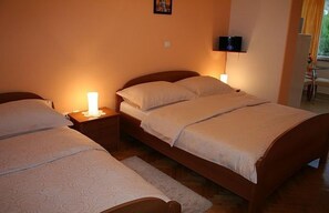 A bedroom with two beds, a nightstand with a lamp, and a wall-mounted TV. - Apartments Vila Paula (Dugi Rat)