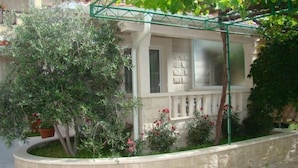 A building with a balcony, a window, and a garden with plants and flowers. - Apartments Vila Paula (Dugi Rat)