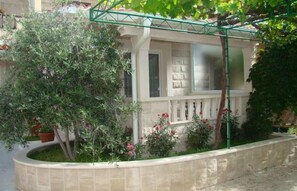 A building with a balcony, a window, and a garden with plants and flowers. - Apartments Vila Paula (Dugi Rat)