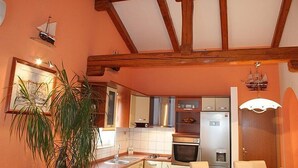 A kitchen with wooden beams, a sink, cabinets, and a refrigerator. - Apartments Vila Paula (Dugi Rat)