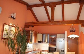 A kitchen with wooden beams, a sink, cabinets, and a refrigerator. - Apartments Vila Paula (Dugi Rat)