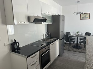 Eine moderne Küche mit Einbauofen, Spüle und Essbereich inklusive Tisch und Stühlen.