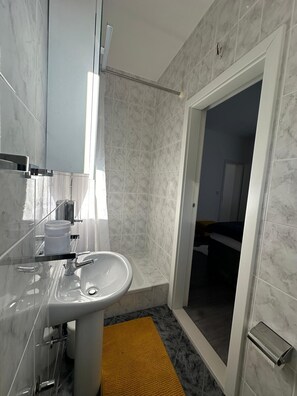 Een moderne badkamer met een wastafel, spiegel en douchehoek.