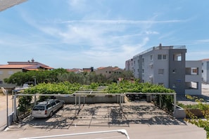 Ein Parkplatz mit einem Auto und einem Lieferwagen, umgeben von Grünflächen und Gebäuden.