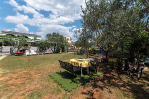 Ein Garten mit Tisch und Stühlen, einer Schaukel und Fahrrädern.