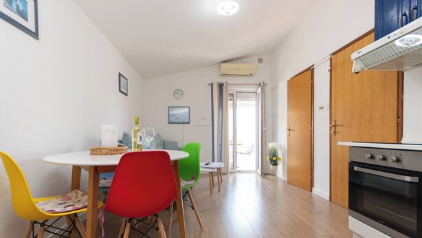 Een keuken met houten kastjes, een fornuis en een eethoek met een tafel en stoelen.