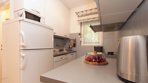 Een moderne keuken met een koelkast, fornuis, magnetron en een roestvrijstalen waterkoker.
