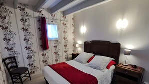 A bedroom with a bed, two bedside tables, a chair, and a window with curtains.