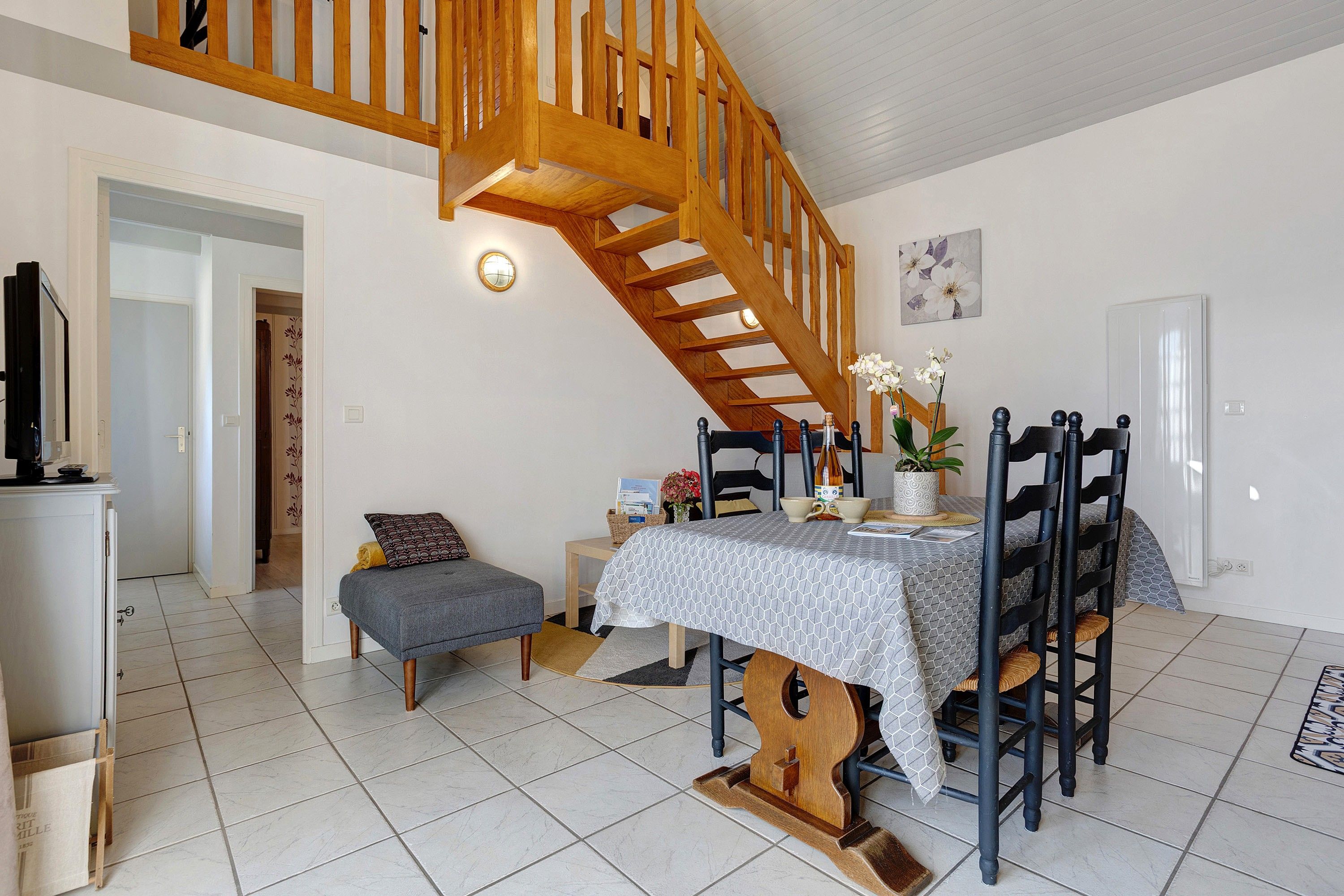 Ein Essbereich mit einer Holztreppe, einem Tisch mit gemustertem Tischläufer und Stühlen mit schwarzen und Holzbeinen.