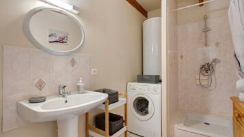 Ein Badezimmer mit Waschbecken, Waschmaschine, Dusche und Toilette.