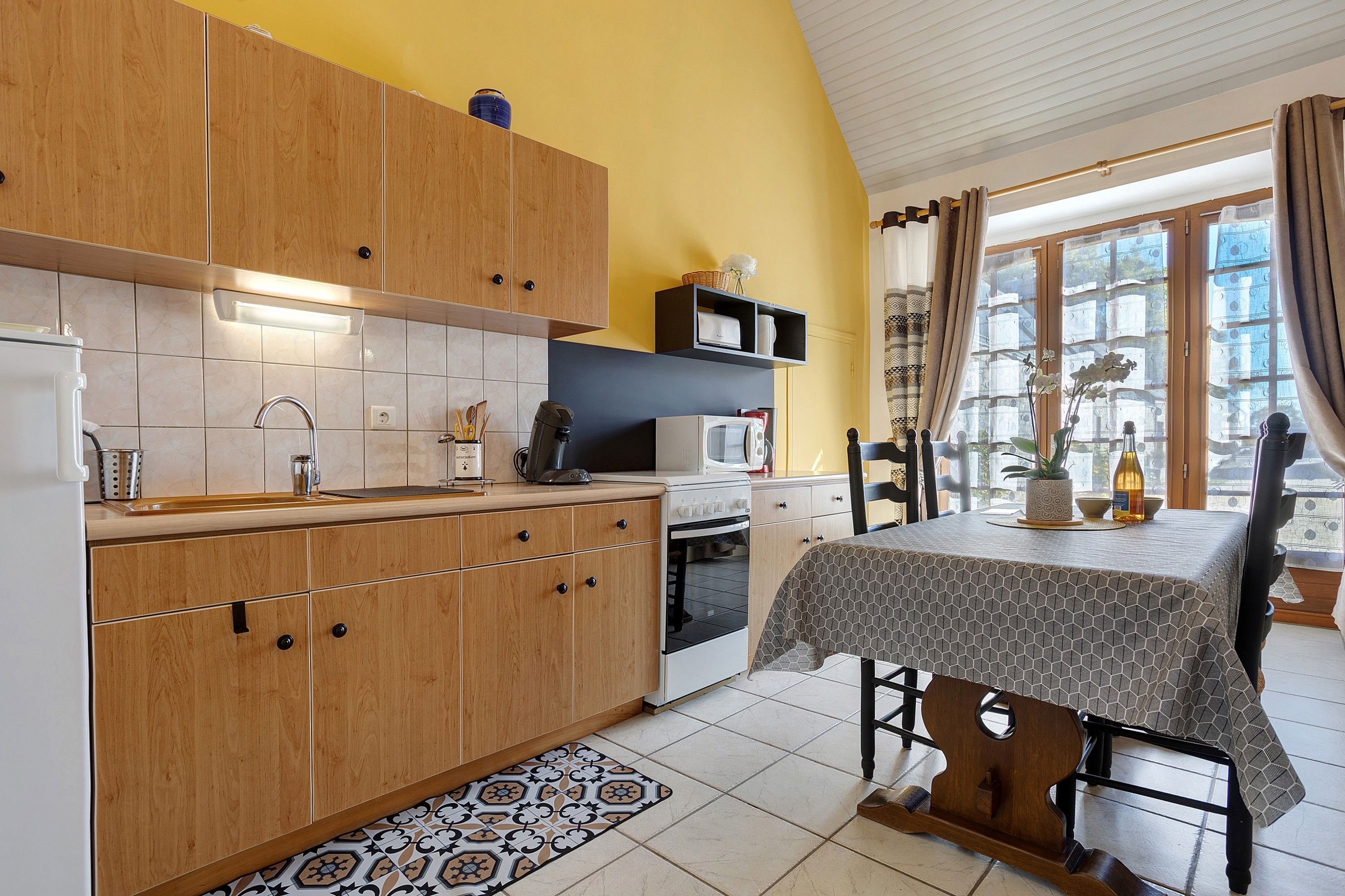 A kitchen with wooden cabinets, a microwave, and a dining area with a table and chairs.