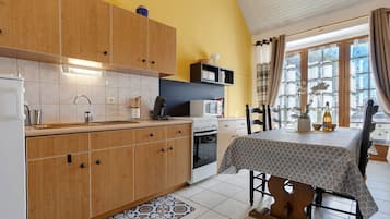 A kitchen with wooden cabinets, a microwave, and a dining area with a table and chairs.