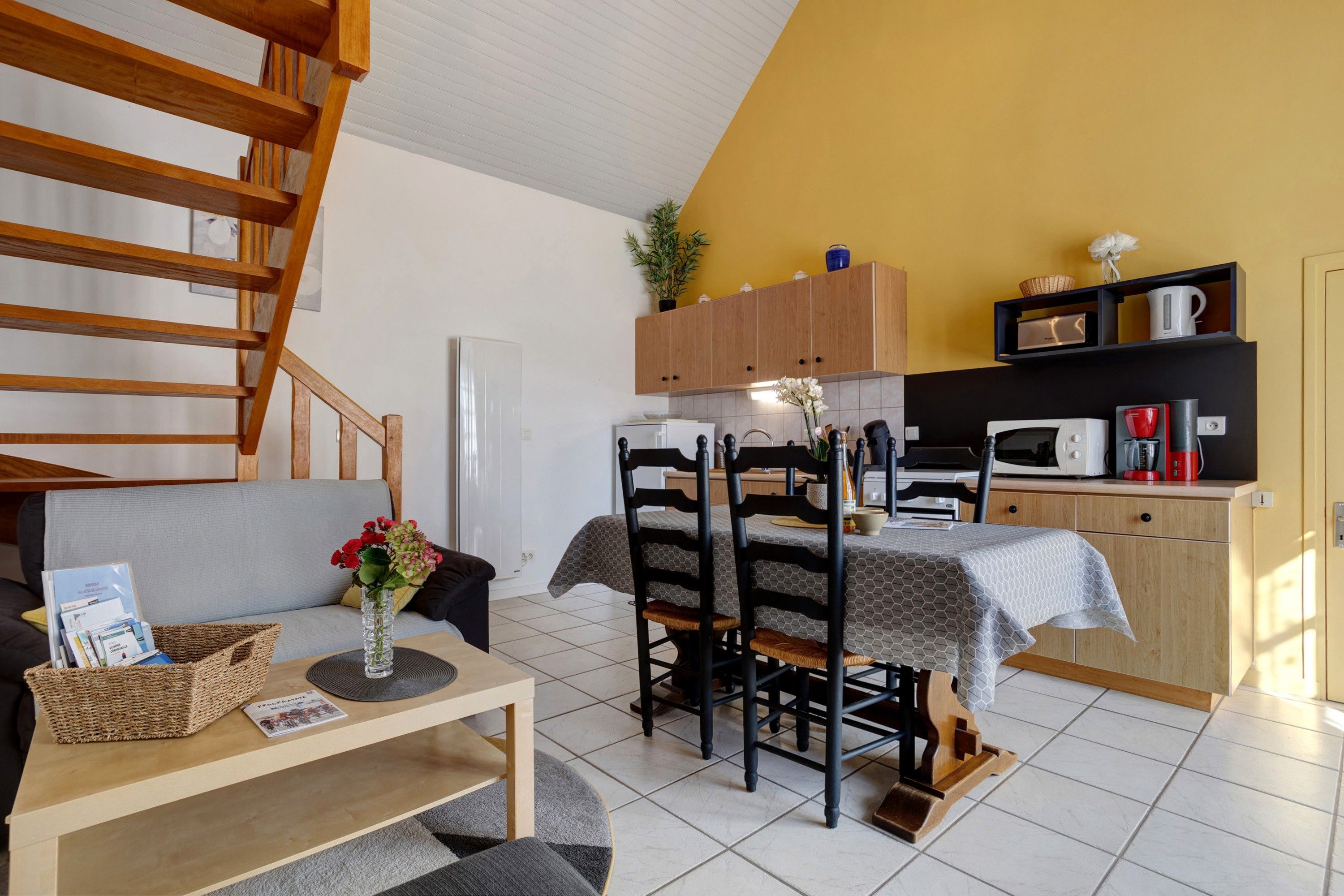 Un espace de vie compact comprenant un coin repas, une cuisine et un escalier.