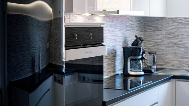 A modern kitchen with a built-in oven, a coffee maker, and a sleek countertop. - Apartments Mladenka 2 (Rab)