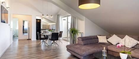 A modern living room with a sofa, coffee table, and dining area.