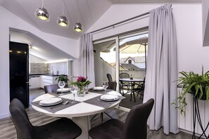 A dining area with a round table, chairs, and a view through a glass door to an outdoor patio. - Apartments Mladenka 2 (Rab)