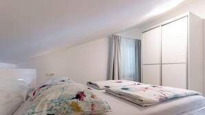 A bedroom with two beds, a window with curtains, and a wardrobe. - Apartments Mladenka 2 (Rab)