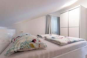 A bedroom with two beds, a window with curtains, and a wardrobe. - Apartments Mladenka 2 (Rab)