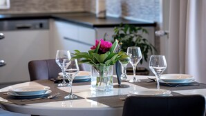 A dining table set with plates, glasses, and a vase with flowers. - Apartments Mladenka 2 (Rab)