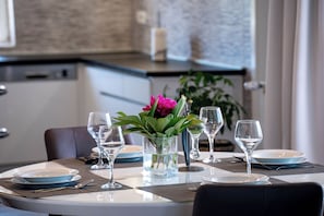 A dining table set with plates, glasses, and a vase with flowers. - Apartments Mladenka 2 (Rab)