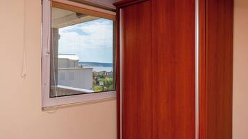 Una habitación con un armario de madera, una ventana con vista a edificios y una masa de agua.