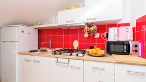 Una cocina con estufa a gas, microondas y armarios blancos.