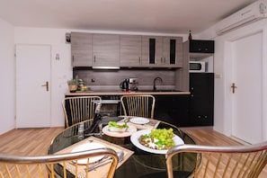 Una cocina compacta con electrodomésticos modernos, una mesa de comedor con sillas y un refrigerador pequeño.
