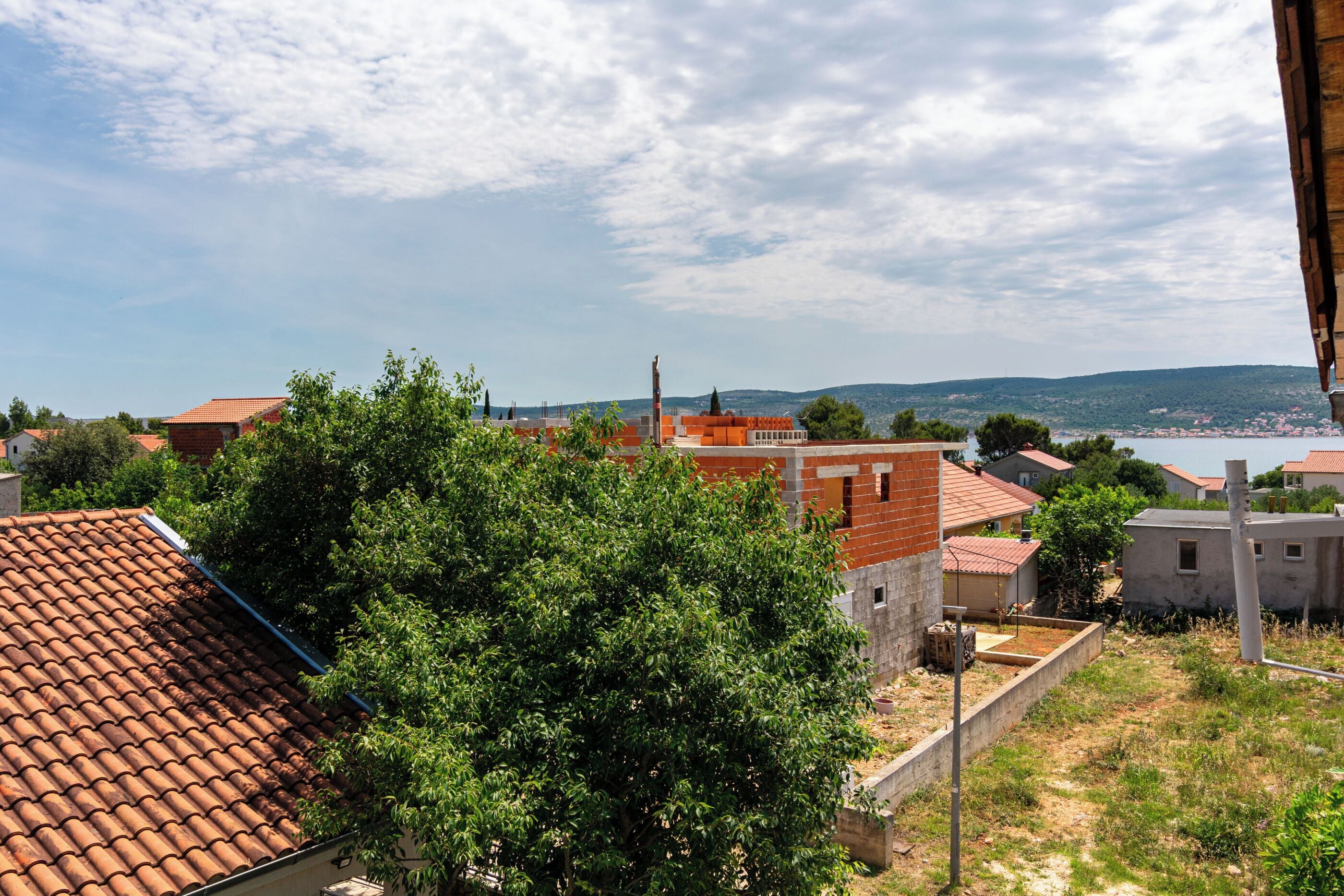 Vista de una zona residencial con casas, árboles y una masa de agua distante.