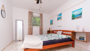 Un dormitorio con cama, ventana con cortinas, mesita de noche y decoración en la pared.